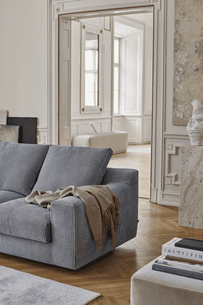 Close-up of striped Aton Mini Sofa by Eilersen with throw blanket, placed in a classic room with elegant trim. Blends comfort with sophisticated design.
