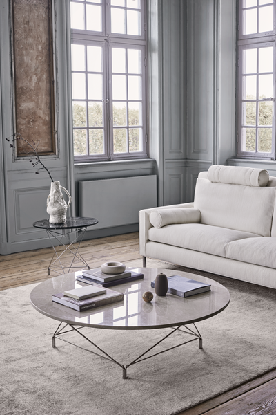 Close-up of the Streamline High Back Sofa by Eilersen in cream, styled with a round marble coffee table and minimalist accessories.