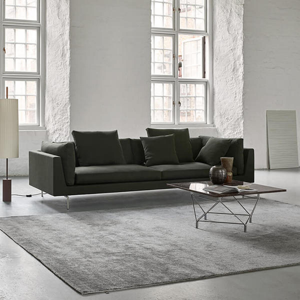 Float High Sectional Sofa by Eilersen in dark green fabric placed in a minimalist room with grey rug and modern coffee table.