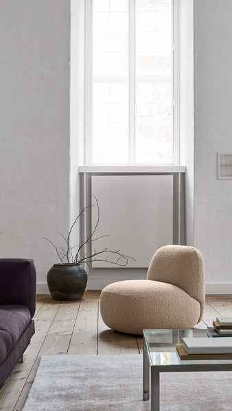 Modern living space with Havana Round Arm Chair by Eilersen in white boucle, styled with a black floor lamp and neutral decor.