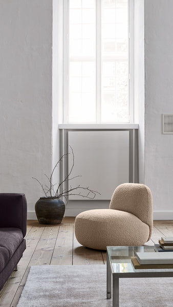Modern living space with Havana Round Arm Chair by Eilersen in white boucle, styled with a black floor lamp and neutral decor.