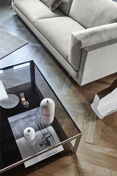 Top view of the Tub Sofa by Eilersen in a light fabric, styled with a glass coffee table and modern decor on herringbone wood flooring.