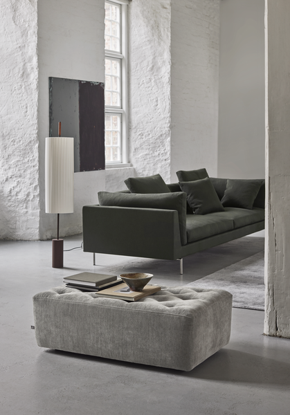 Side angle of Float High Sectional Sofa by Eilersen in dark green upholstery, styled in a bright room with modern decor.