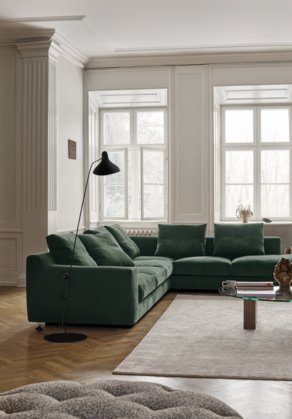 Aton Mini Sofa by Eilersen in deep green fabric placed in a classic living room with natural light and wood flooring. Compact luxury seating for modern interiors.