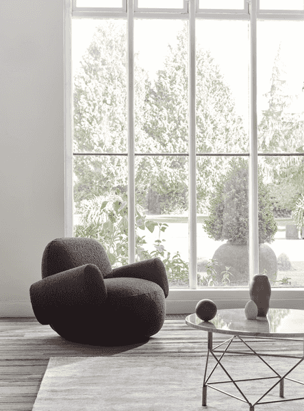 Minimalist corner with Havana Lounge Chair by Eilersen in light fabric, styled with a wood bench and brass floor lamp.