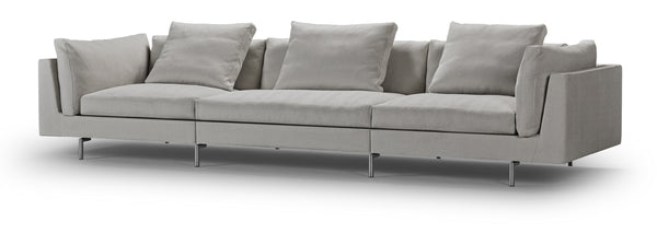 Angled view of Float High Sectional Sofa by Eilersen in light grey fabric, highlighting its long modular seating and slim legs.