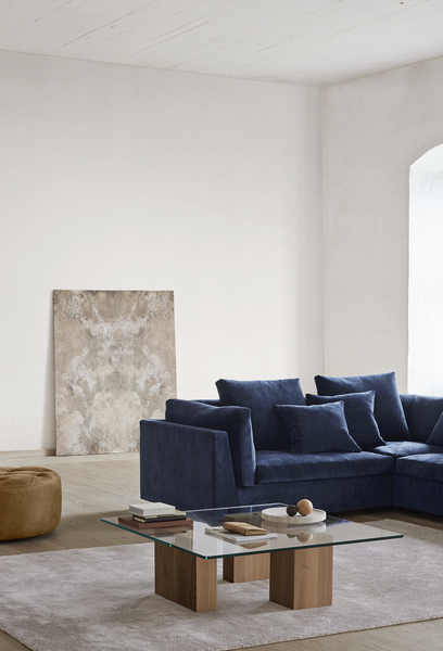 Corner view of navy Float Sofa sectional by Eilersen with glass coffee table. Offered at Trade Source Furniture with fabric customization.