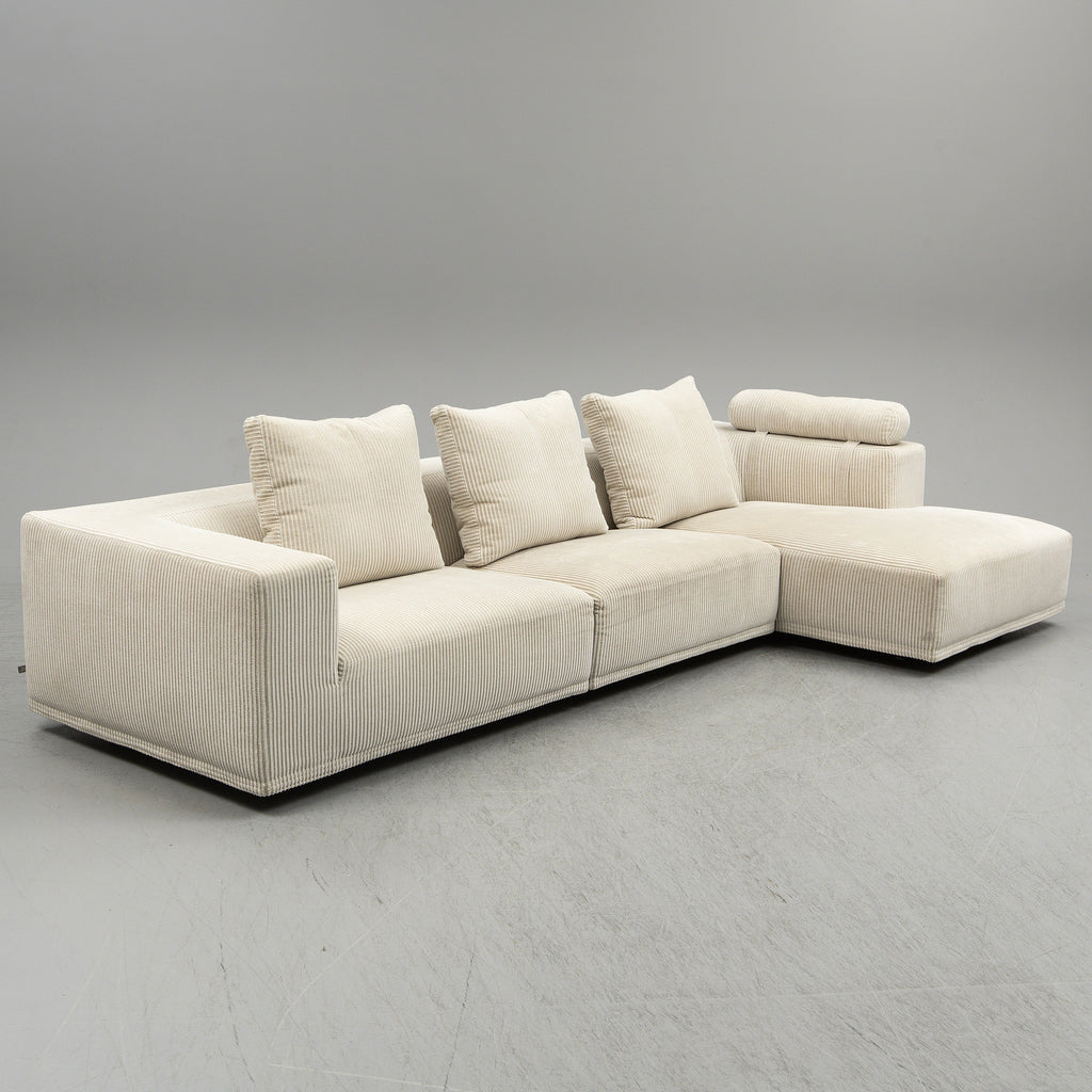 Angled view of the Quick Ship Baseline Sofa by Eilersen in cream corduroy, showcasing its modular design and plush seating.