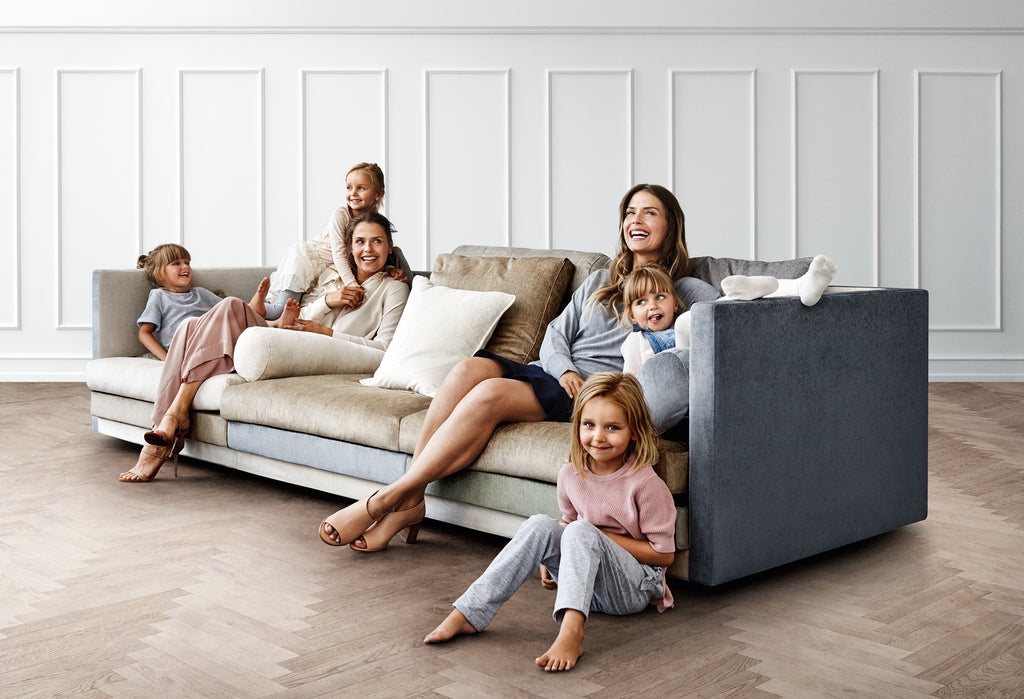 Family enjoying the Cocoon Sofa by Eilersen at Trade Source Furniture, upholstered in a two-tone fabric with plush cushions in a bright living room.