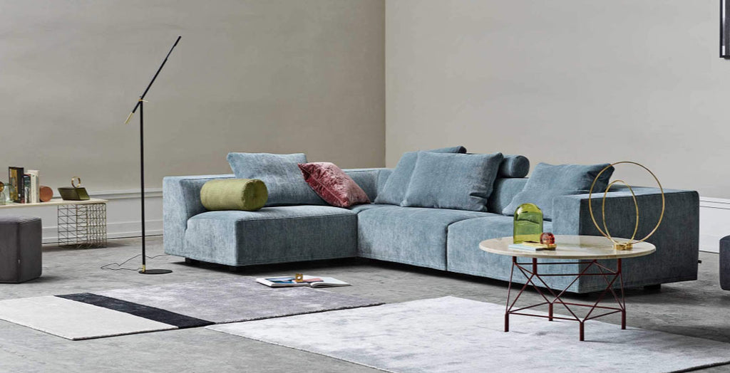 Quick Ship Baseline Sofa with Chaise by Eilersen in blue velvet, styled in a contemporary setting with modern lighting and geometric rugs.