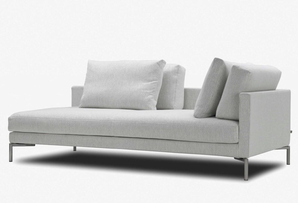 Angled view of Eilersen Plano Sofa in light grey, featuring slim metal legs and plush back cushions for modern comfort.