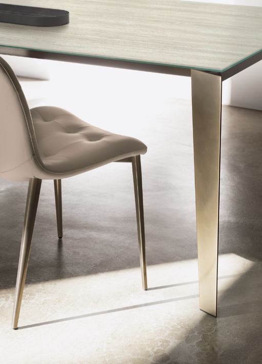 Elegant Italian furniture design featuring a modern dining table with a sleek glass top and metallic gold legs, exemplifying Bontempi's instant classics.
