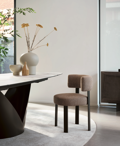 Contemporary dining room with Calligaris's 2026 collection chair featuring modern design, brown upholstered seat, and black metal legs, paired with minimalist decor and natural light.