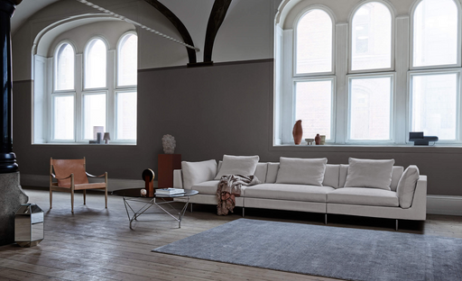 Elegant modern living room with large arched windows, white sectional sofa, minimalist coffee table, and contemporary decor in a spacious, airy setting.