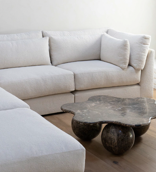 A luxurious, plush white sofa with multiple cushions in a modern living room, paired with a unique dark marble coffee table, creating a cozy and elegant ambiance.