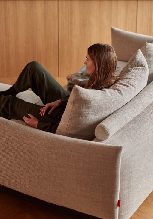 A woman relaxing on a modern living room sofa bed with plush cushions, showcasing the versatile design of New Innovation Living Sofa Beds for 2021.