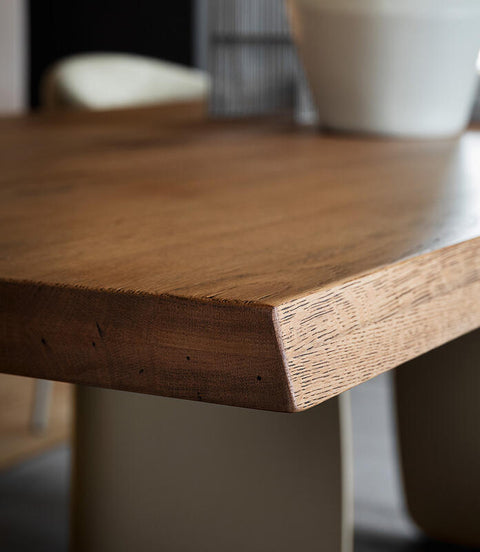 Close-up of a wooden dining table with a wider shot of a dining room setup.