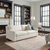 Living room with a white sofa, bookshelves, and large windows.
