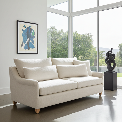 Beige sofa in a modern living room with large windows and abstract art.