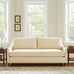 Beige sofa in a living room with large windows and light decor