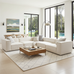 Modern living room with a white sectional sofa, wooden coffee table, and large windows.