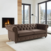 Brown Chesterfield sofa in a living room with a fireplace and large windows.