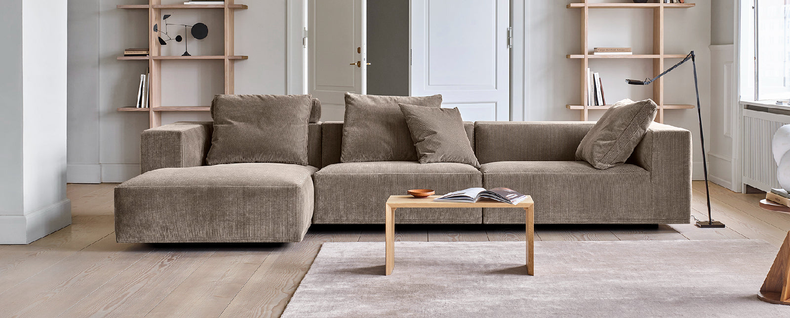 Gray sectional sofa in a modern living room with a coffee table and shelves.