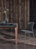 Stylish gray upholstered dining chair with a curved back and metal legs, placed in a rustic wooden interior