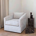 Modern armchair in a room with a marble side table and decorative item.
