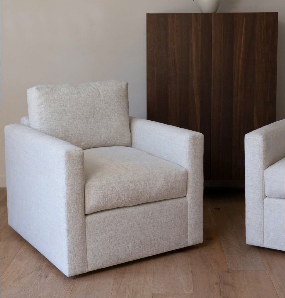 Beige armchair in a room with a wooden floor and a dark brown cabinet.