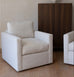 Beige armchair in a room with a wooden floor and a dark brown cabinet.